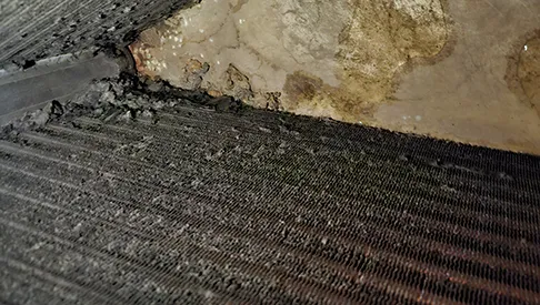 A coil with its fins packed with dust and debris